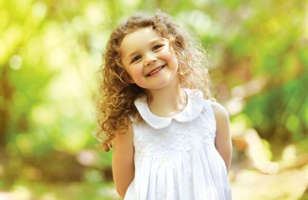Curly little girl wearing a white dress