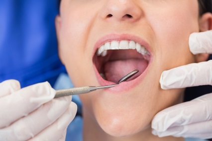 Dentist examining a patient with angle mirror in dental clinic